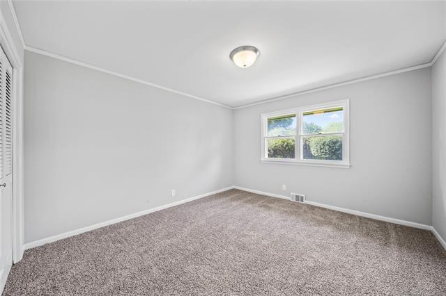 empty room with visible vents, ornamental molding, baseboards, and carpet floors