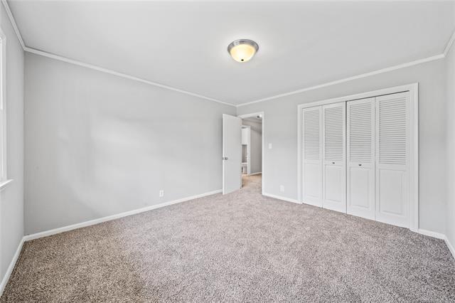 unfurnished bedroom featuring crown molding, carpet, a closet, and baseboards