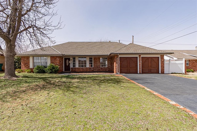 ranch-style house featuring brick siding, an attached garage, aphalt driveway, and fence