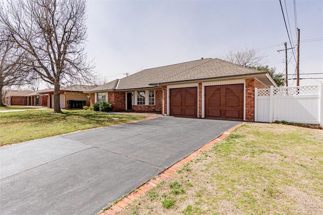 ranch-style home with brick siding, a front lawn, fence, a garage, and driveway