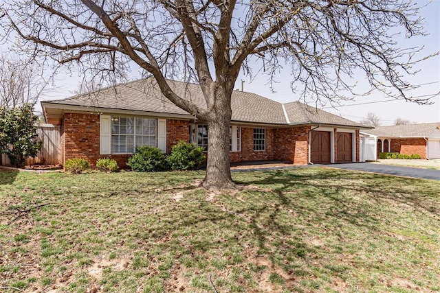 ranch-style house featuring brick siding, an attached garage, a shingled roof, and aphalt driveway