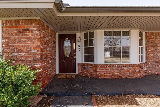 entrance to property featuring brick siding and a porch