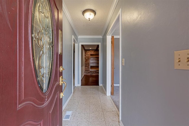 corridor with visible vents, crown molding, baseboards, light floors, and a textured ceiling