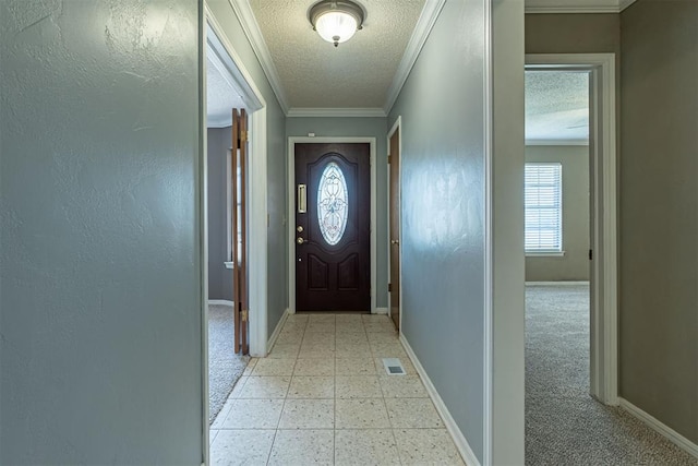 entryway with visible vents, baseboards, light floors, ornamental molding, and a textured ceiling