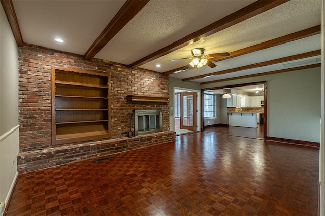 unfurnished living room featuring built in features, baseboards, beam ceiling, ceiling fan, and a textured ceiling