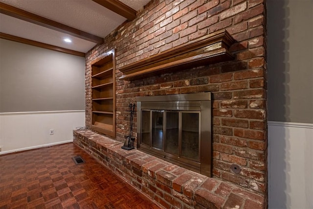 details with visible vents, built in shelves, a wainscoted wall, beam ceiling, and a textured ceiling