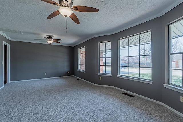 spare room with visible vents, carpet, crown molding, baseboards, and ceiling fan