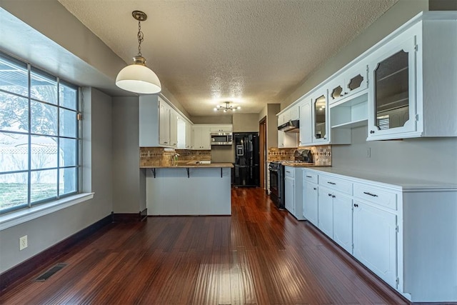 kitchen with visible vents, glass insert cabinets, dark wood-type flooring, a peninsula, and black appliances