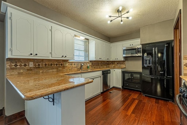 kitchen featuring a sink, white cabinetry, appliances with stainless steel finishes, a peninsula, and dark wood-style flooring