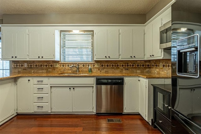 kitchen featuring visible vents, backsplash, dark wood-style floors, stainless steel appliances, and a sink