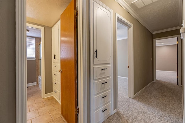 hallway with light carpet, ornamental molding, baseboards, and a textured ceiling