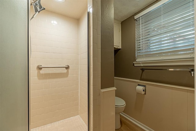 full bath with a wainscoted wall, a stall shower, toilet, and wood finished floors