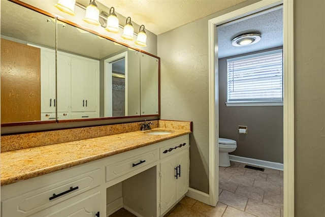 bathroom with vanity, baseboards, visible vents, a textured ceiling, and toilet