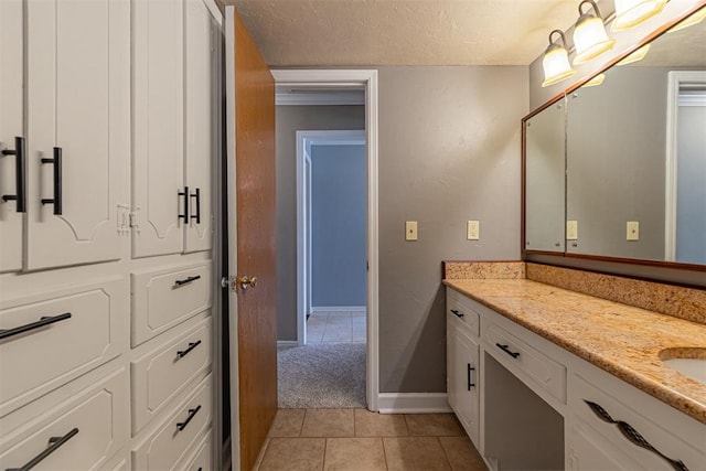 bathroom with tile patterned flooring, vanity, baseboards, and a textured ceiling