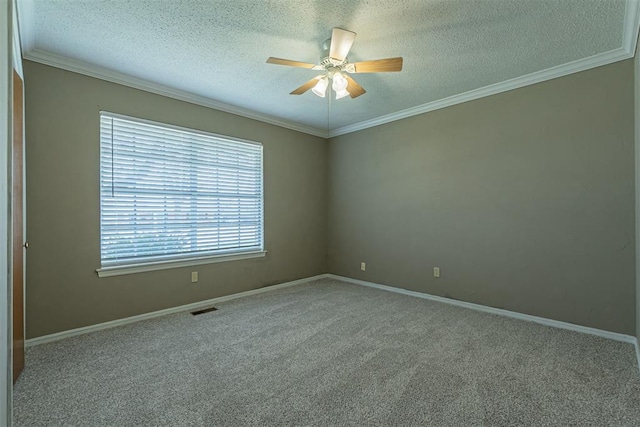 carpeted empty room featuring visible vents, a ceiling fan, a textured ceiling, crown molding, and baseboards