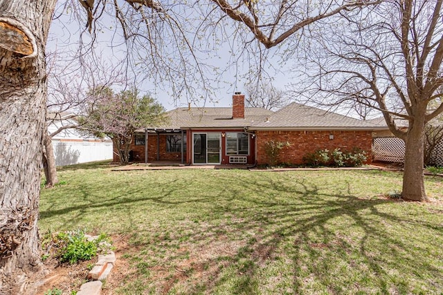 back of house with fence, a lawn, brick siding, and a chimney