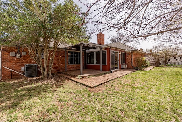 back of property featuring brick siding, central AC, a chimney, a yard, and a patio area