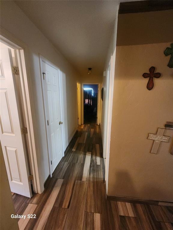 hallway featuring baseboards and dark wood-style floors