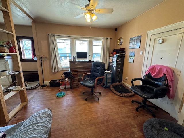 home office featuring a textured ceiling, ceiling fan, and wood finished floors