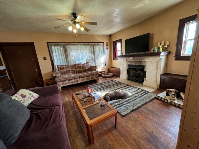 living area with ceiling fan, a fireplace, and wood finished floors