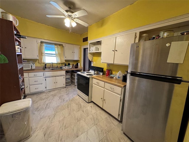 kitchen with freestanding refrigerator, range with electric stovetop, ceiling fan, white microwave, and a sink