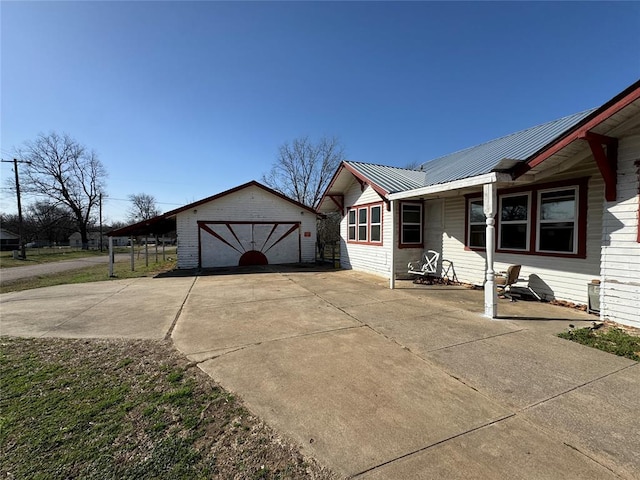 view of side of home featuring an outdoor structure, a detached garage, and metal roof
