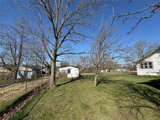 view of yard featuring an outdoor structure, a shed, and fence