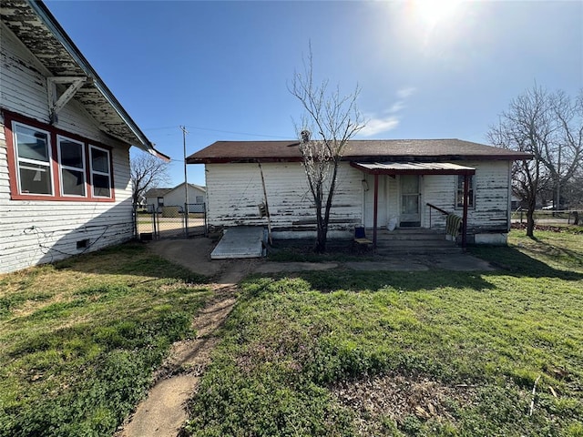 rear view of property with fence, a gate, crawl space, entry steps, and a yard