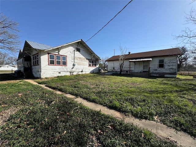 view of side of property with a yard, crawl space, and entry steps