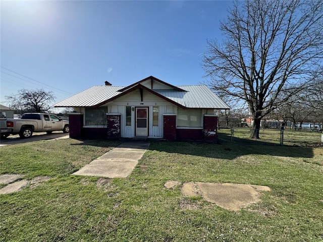 view of front of property featuring metal roof and a front yard