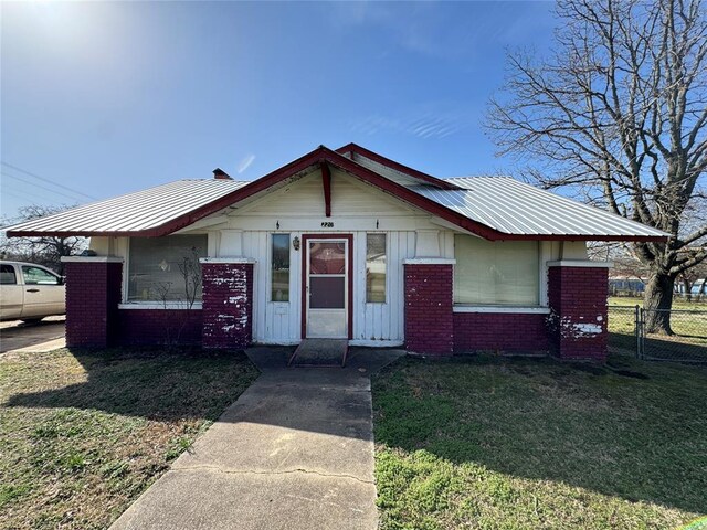 bungalow-style house featuring brick siding, a front lawn, board and batten siding, and fence