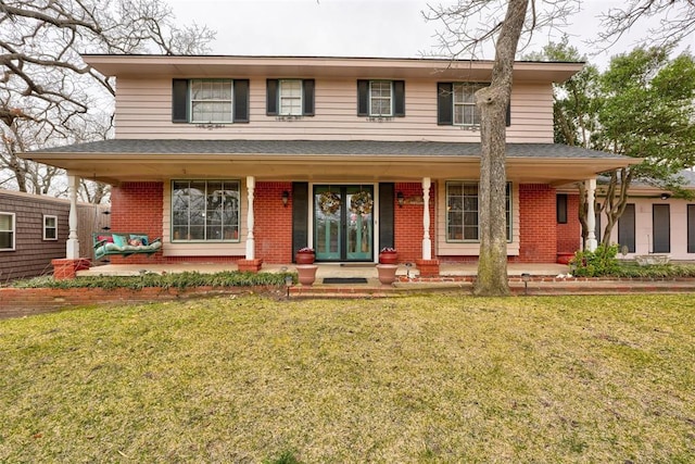 view of front of property with a front yard, a porch, and brick siding