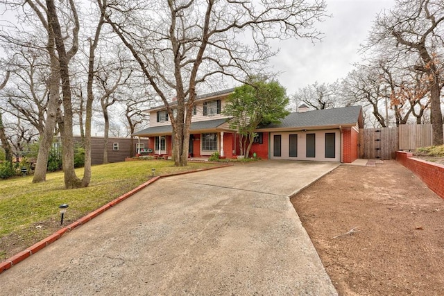 view of front of house featuring a gate, fence, concrete driveway, a front yard, and brick siding