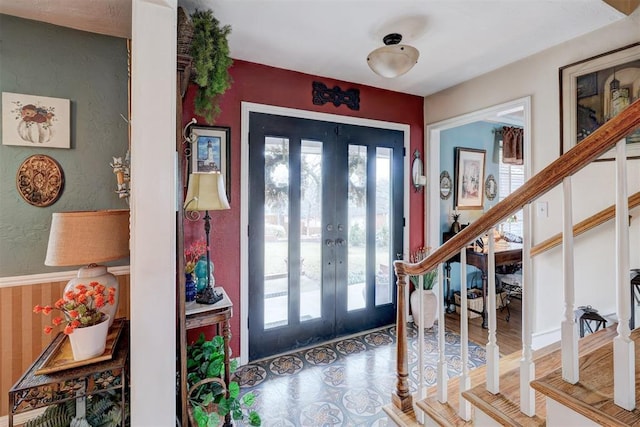 foyer entrance with wood finished floors, stairway, and french doors