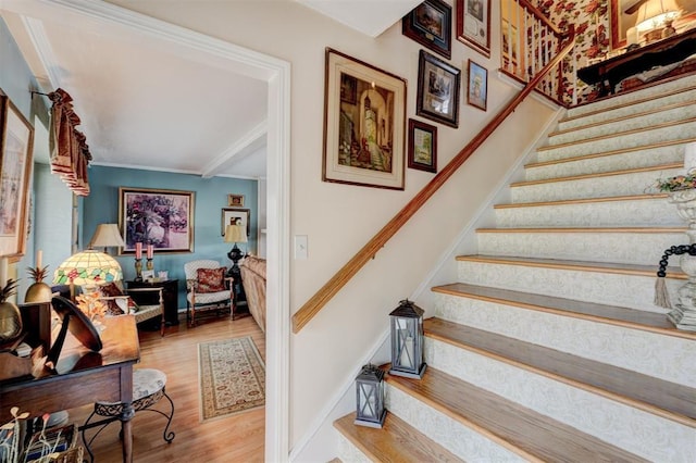 stairway featuring wood finished floors, baseboards, and ornamental molding