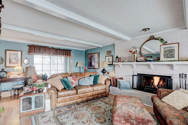 living room with wood finished floors, a fireplace, ornamental molding, a textured ceiling, and beamed ceiling