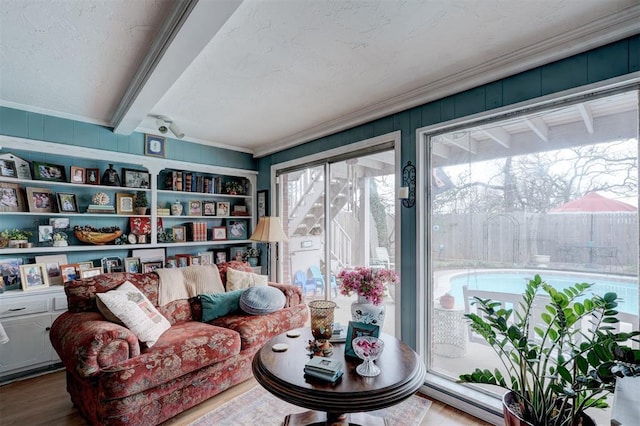 living area featuring beamed ceiling, a textured ceiling, crown molding, and wood finished floors