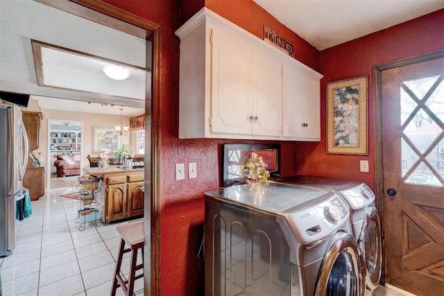 washroom featuring an inviting chandelier, separate washer and dryer, light tile patterned flooring, and cabinet space