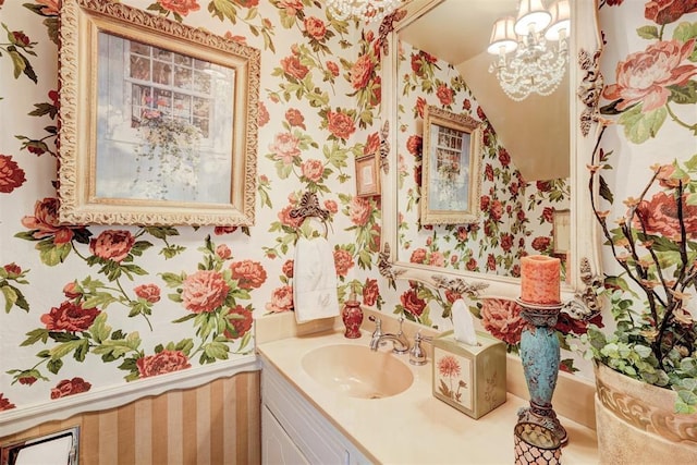 bathroom featuring wallpapered walls, vanity, and an inviting chandelier