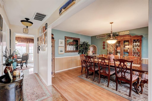 dining room featuring visible vents, wainscoting, and light wood-type flooring