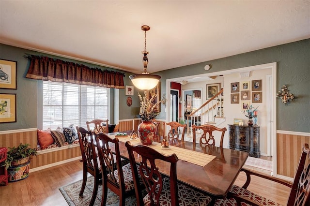 dining space featuring wood finished floors, wainscoting, and a textured wall