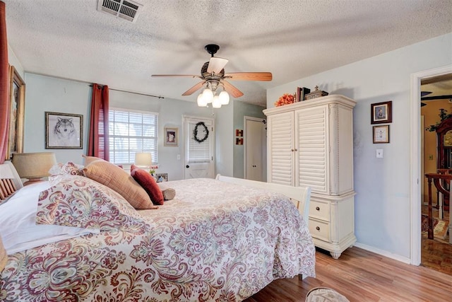 bedroom featuring ceiling fan, a textured ceiling, visible vents, and light wood-type flooring