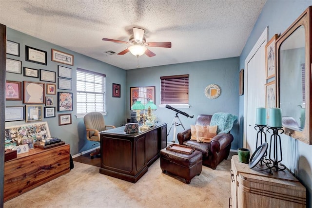 home office featuring visible vents, light colored carpet, a ceiling fan, and a textured ceiling