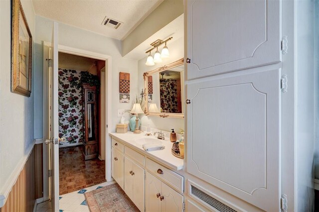 bathroom with visible vents, a textured ceiling, and vanity