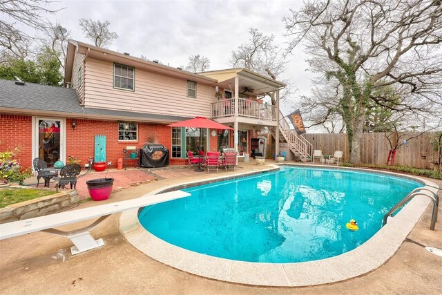 view of pool with a patio, stairway, a ceiling fan, fence, and a diving board