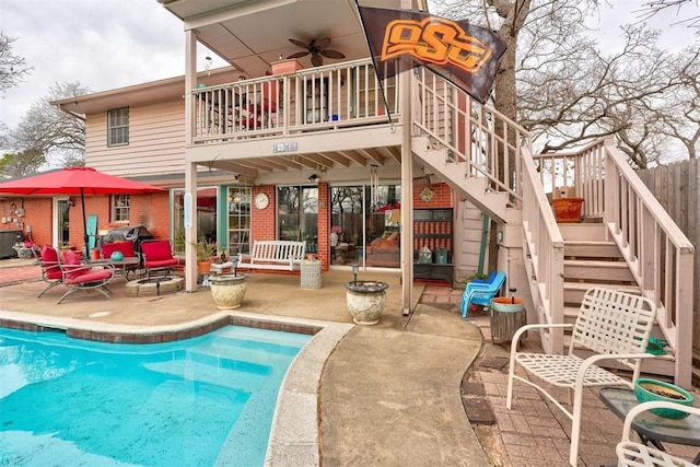 back of house featuring a ceiling fan, stairway, a fenced in pool, brick siding, and a patio area