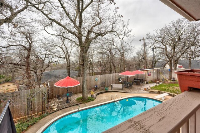 view of swimming pool featuring a fenced in pool, a wooden deck, and a fenced backyard