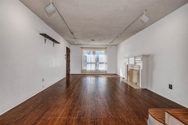 unfurnished living room with baseboards, a textured ceiling, hardwood / wood-style floors, and a tiled fireplace