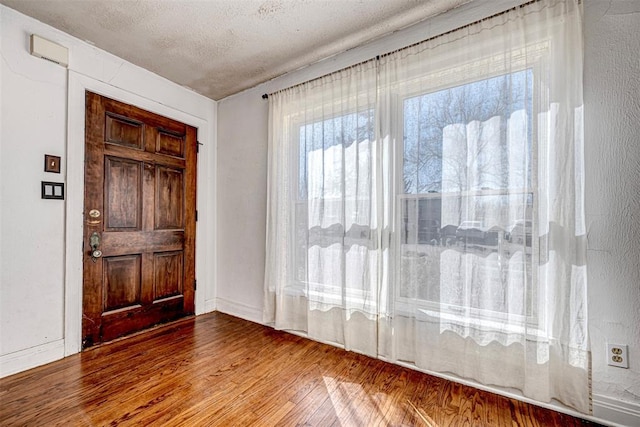 entryway with wood-type flooring and a textured ceiling