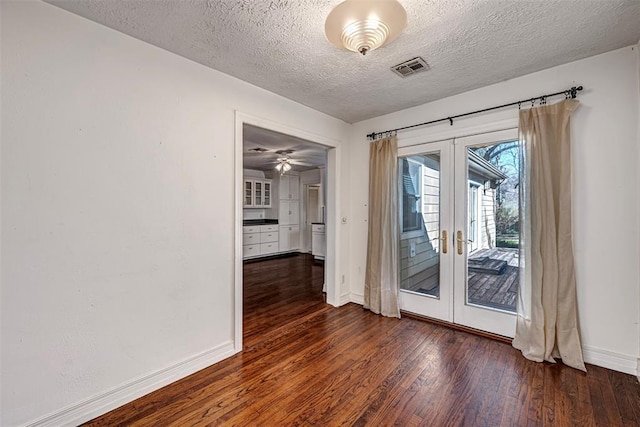 spare room with visible vents, baseboards, dark wood-type flooring, french doors, and a textured ceiling